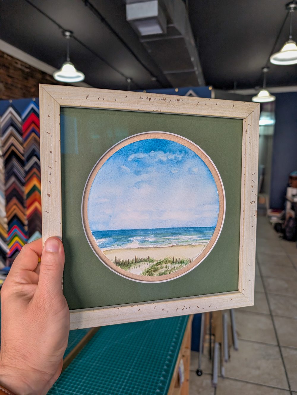 Circular mat cut with beach watercolor in a birch frame